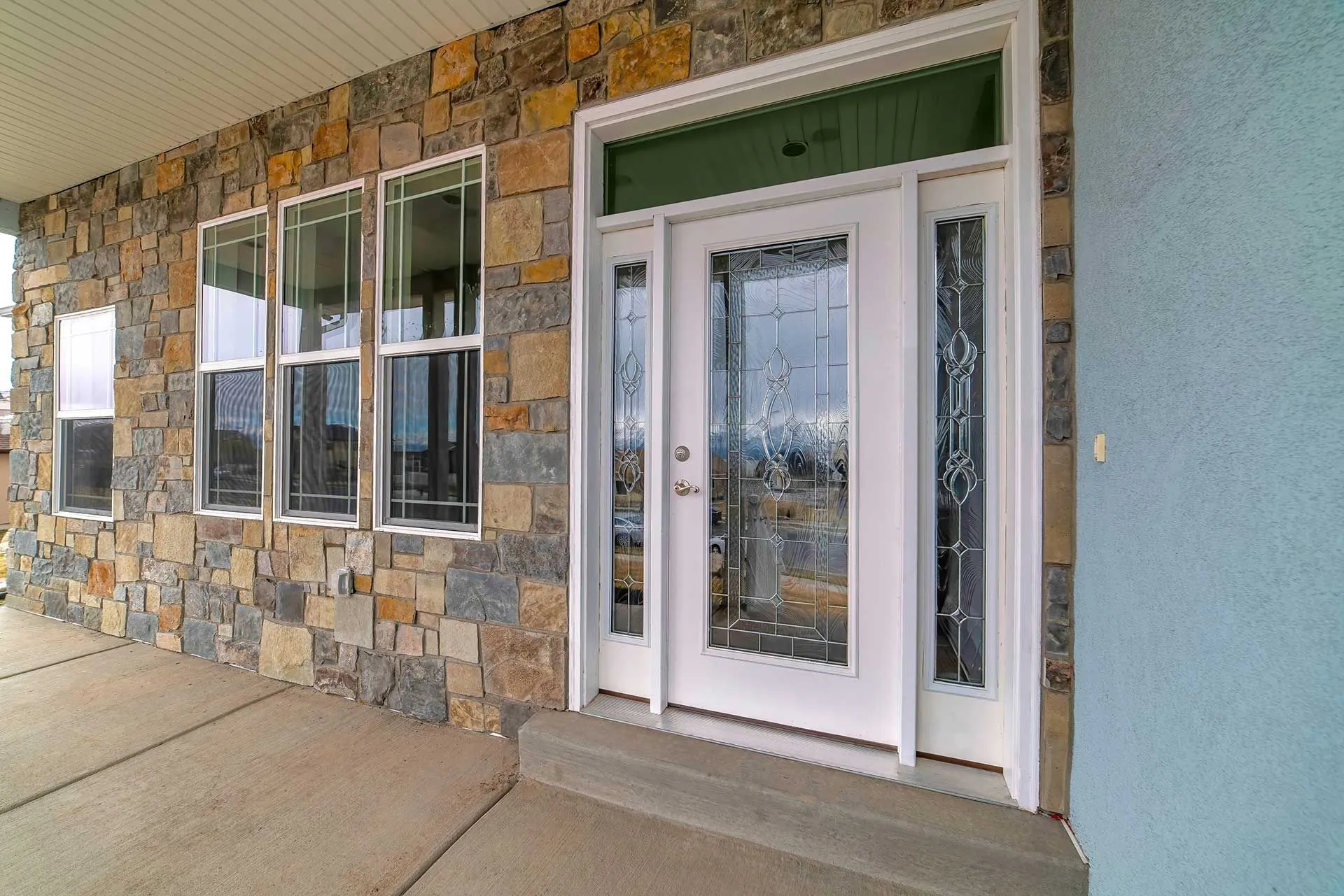 White entry door with decorative glass on stone